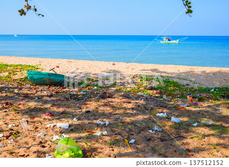 Trash on sea beach, fishing boat in distance. Garbage dump at ocean. Trash, debris on beach. Trash on sea beach, fishing boat in distance. Garbage dump at ocean. Trash, debris on beach. 137512152
