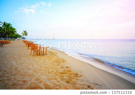 Dining on sand beach. People swim in ocean shoreon. Sea resort beach. Table, chair on in restaurant. Dining on sand beach. People swim in ocean shoreon. Sea resort beach. Table, chair on in restaurant. 137512158