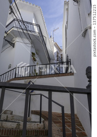 Walking through the narrow streets of Frigiliana, Spain with white houses and stairways on a sunny day 137512215