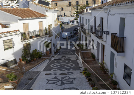 Streets of Frigiliana show white houses and patterned stone walkways during a clear day Streets of Frigiliana show white houses and patterned stone walkways during a clear day 137512224