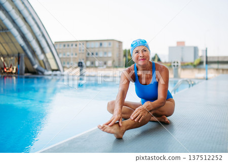 Older female swimmer stretching before swim in pool. 137512252