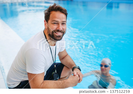 Coach giving advice to young swimmer, walking by pool. Coach giving advice to young swimmer, walking by pool. 137512259