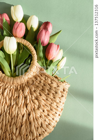 Tulip Bouquet in Straw Handbag. Stylish Spring Floral Composition on Green Background Tulip Bouquet in Straw Handbag. Stylish Spring Floral Composition on Green Background 137512316