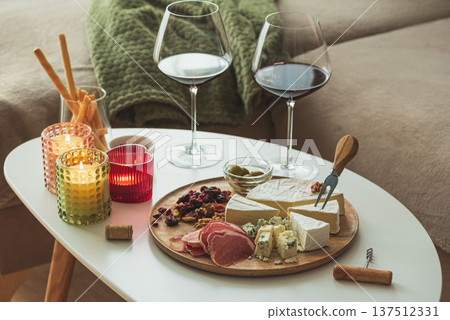 Cozy living room with two glasses of red wine and cheese on table Cozy living room with two glasses of red wine and cheese on table 137512331