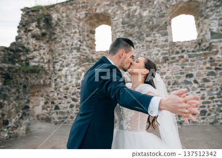 Bride and groom dancing, looking at each other. Wedding couple standing outside near ruins. 137512342
