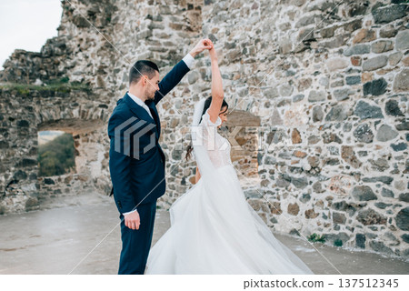 Bride and groom dancing, looking at each other. Wedding couple standing outside near ruins. Bride and groom dancing, looking at each other. Wedding couple standing outside near ruins. 137512345