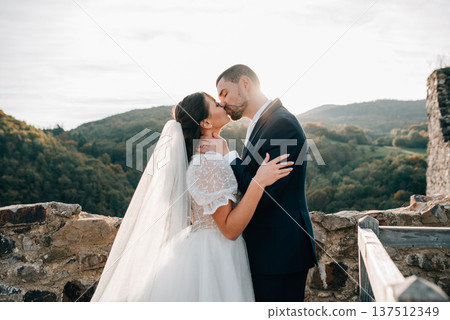 Young wedding couple kissing, standing outside near ruins. 137512349