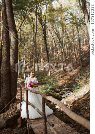 Bride in a snow-white wedding dress in nature, surrounded by a forest. Bride in a snow-white wedding dress in nature, surrounded by a forest. 137512358