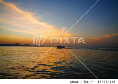 Boat moves sea on sunset near coastline in tropical island. Boat travels in ocean under sunset. Boat moves sea on sunset near coastline in tropical island. Boat travels in ocean under sunset. 137512456