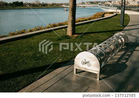 Bicycle parking rack installed along riverside promenade near the water. Urban cycling infrastructure and pedestrian walkway in Belgrade Bicycle parking rack installed along riverside promenade near the water. Urban cycling infrastructure and pedestrian walkway in Belgrade 137512585