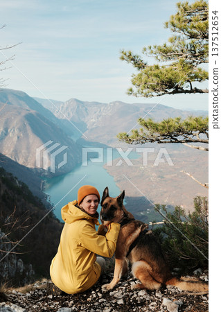 A woman gently hugs a German Shepherd on viewpoint above the Drina river canyon in Tara National park, Serbia. Concept of trust companionship and outdoor adventure with dogs A woman gently hugs a German Shepherd on viewpoint above the Drina river canyon in Tara National park, Serbia. Concept of trust companionship and outdoor adventure with dogs 137512654