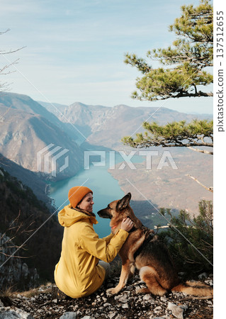 A woman gently hugs a German Shepherd on viewpoint above the Drina river canyon in Tara National park, Serbia. Concept of trust companionship and outdoor adventure with dogs A woman gently hugs a German Shepherd on viewpoint above the Drina river canyon in Tara National park, Serbia. Concept of trust companionship and outdoor adventure with dogs 137512655