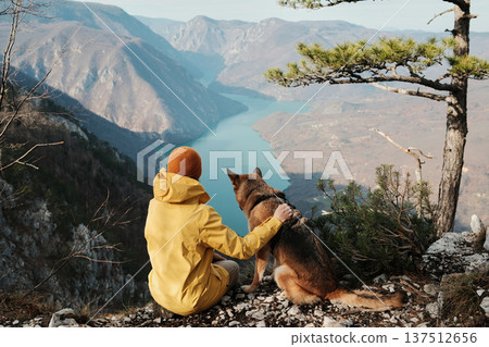A woman gently hugs a German Shepherd on viewpoint above the Drina river canyon in Tara National park, Serbia. Concept of trust companionship and outdoor adventure with dogs A woman gently hugs a German Shepherd on viewpoint above the Drina river canyon in Tara National park, Serbia. Concept of trust companionship and outdoor adventure with dogs 137512656