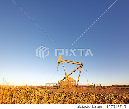 Pump jack (nodding donkey) on a desert at sunset. Pump jack (nodding donkey) on a desert at sunset. 137512745