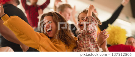 Excited football fans, mother with little daughter, supporting German national team in live soccer match at stadium. Excited football fans, mother with little daughter, supporting German national team in live soccer match at stadium. 137512805