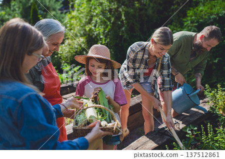 Happy farmer family looking at their harvest outdoors in garden. Happy farmer family looking at their harvest outdoors in garden. 137512861