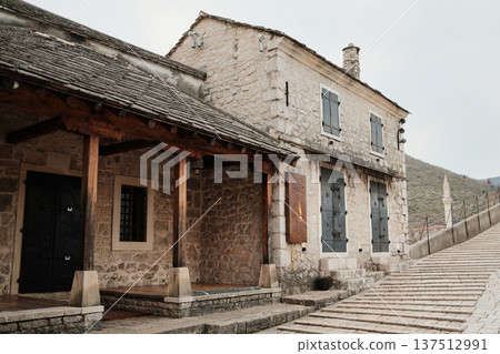 Stone house near the Old Bridge in Mostar with wooden porch and historic pavement. Traditional Balkan architecture showing preserved heritage and old town atmosphere 137512991