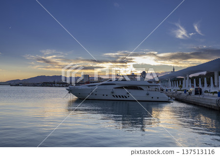 Sunset over the harbor in Malaga, Spain with a yacht docked at the marina during the evening Sunset over the harbor in Malaga, Spain with a yacht docked at the marina during the evening 137513116