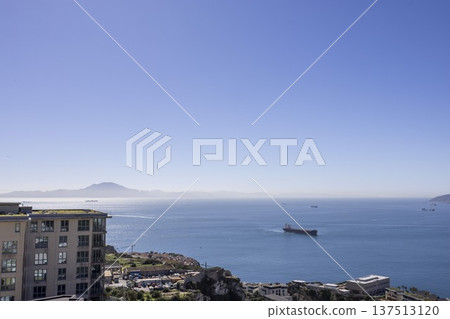 Ships travel across the sea near Gibraltar with clear skies and distant mountains in view Ships travel across the sea near Gibraltar with clear skies and distant mountains in view 137513120
