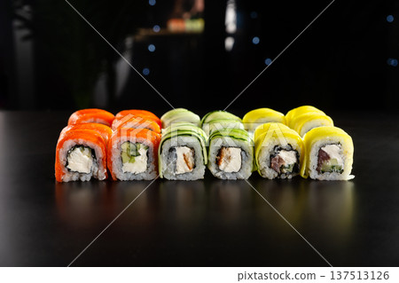 Freshly prepared colorful sushi rolls with salmon, cucumber, and omelet on a black background Freshly prepared colorful sushi rolls with salmon, cucumber, and omelet on a black background 137513126