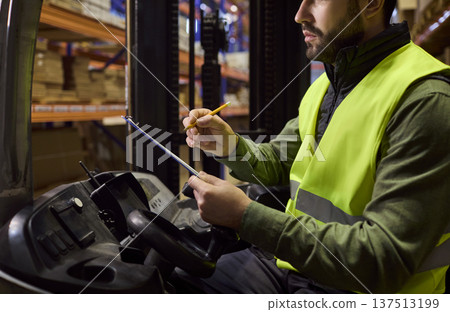 Close up of warehouse forklift operator reviewing checklist for logistics 137513199