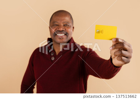 Smiling african american man showing yellow credit card at camera Smiling african american man showing yellow credit card at camera 137513662