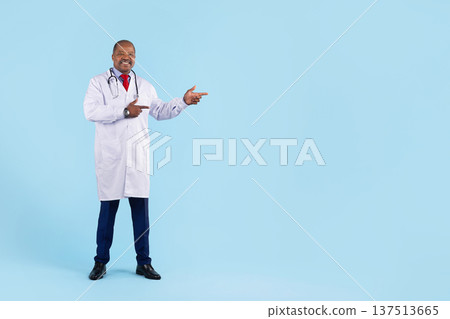 Black doctor in white coat with stethoscope pointing aside on blue background 137513665