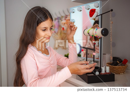 Teen girl choosing jewelry from her vanity at home Teen girl choosing jewelry from her vanity at home 137513734