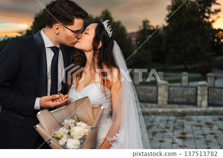 Happy bride and groom sharing a romantic kiss at sunset 137513782