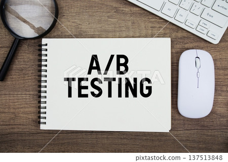 A/B Testing text written on notepad with keyboard, optical mouse and magnifying glass on wooden background 137513848