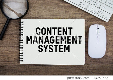 Content Management System text written on notepad with keyboard, optical mouse and magnifying glass on wooden background 137513850
