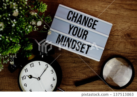 Change Your Mindset text in lightbox with magnifying glass and alarm clock flat lay on wooden background Change Your Mindset text in lightbox with magnifying glass and alarm clock flat lay on wooden background 137513863