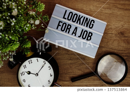Looking for a Job text in lightbox with magnifying glass and alarm clock flat lay on wooden background Looking for a Job text in lightbox with magnifying glass and alarm clock flat lay on wooden background 137513864