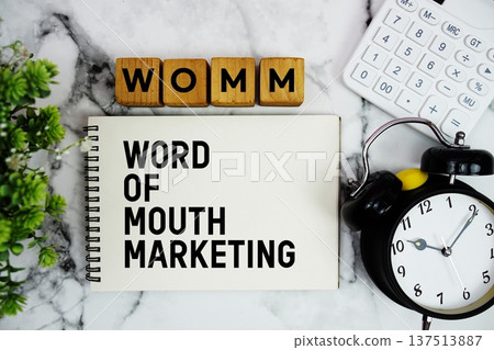 WOMM Word Of Mouth Marketing text with calculator and alarm clock on marble background WOMM Word Of Mouth Marketing text with calculator and alarm clock on marble background 137513887