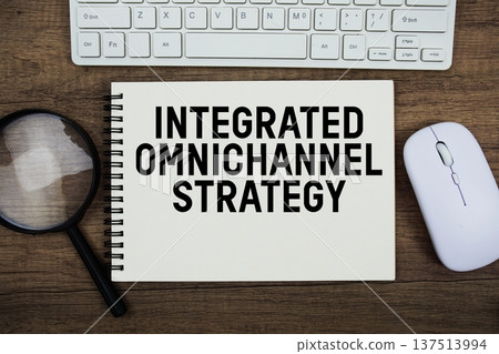 Integrated Omnichannel Strategy text written on notepad with keyboard, optical mouse and magnifying glass on wooden background 137513994