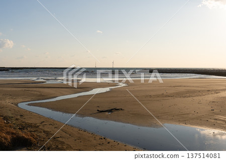A small river flowing along the sandy beach towards the sea A small river flowing along the sandy beach towards the sea 137514081