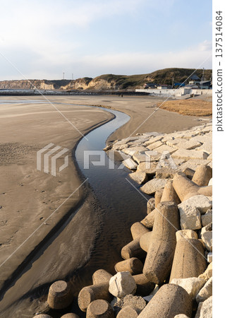 A small river flowing along the sandy beach towards the sea 137514084