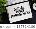 Digital Asset Management text written on notepad with keyboard and alarm clock on black background 137514180