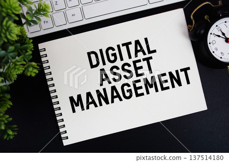 Digital Asset Management text written on notepad with keyboard and alarm clock on black background Digital Asset Management text written on notepad with keyboard and alarm clock on black background 137514180