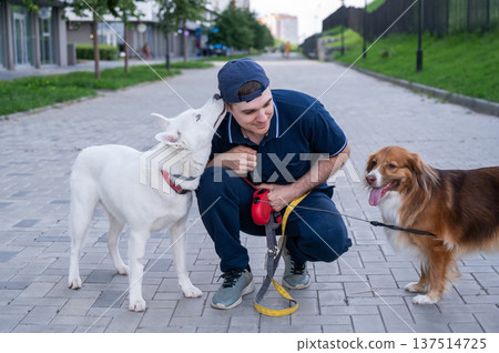 A man hugs his two dogs while on a walk.  137514725