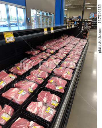 Pork cuts are arranged in a grocery store meat case. Bright price tags and yellow labels sit on the trays. 137514883