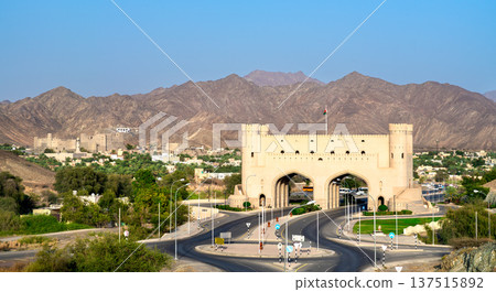 The monumental Bahla Gate serves as an entry to the ancient town, set against Bahla Fort and the arid Hajar mountain range in the Al Dakhiliyah region of Oman. 137515892