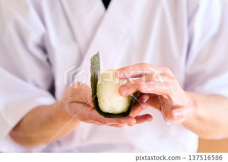 一位廚師正在用海苔包裹飯糰 137516586