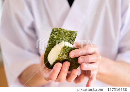 A chef wrapping seaweed around rice balls 137516588