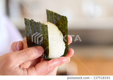 一位廚師正在用海苔包裹飯糰 一位廚師正在用海苔包裹飯糰 137516591