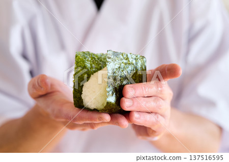 一位廚師正在用海苔包裹飯糰 一位廚師正在用海苔包裹飯糰 137516595