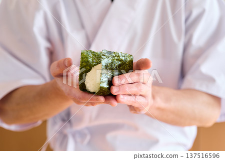 一位廚師正在用海苔包裹飯糰 137516596