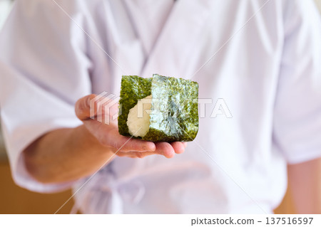 一位廚師正在用海苔包裹飯糰 一位廚師正在用海苔包裹飯糰 137516597