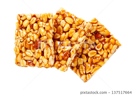 Three pieces of Brazilian peanut brittle made with roasted peanuts and shiny caramel, isolated on a white background. A typical Brazilian sweet 137517664