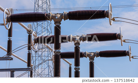 Close up view of various elements and high-voltage insulators of a transformer substation, without people, at daytime on background of blue sky Close up view of various elements and high-voltage insulators of a transformer substation, without people, at daytime on background of blue sky 137518642